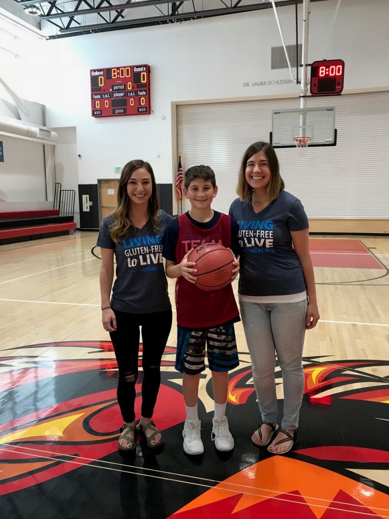 Jackson Resin stands with a basketball alongside Laura Boone and Jena Fellenzer.